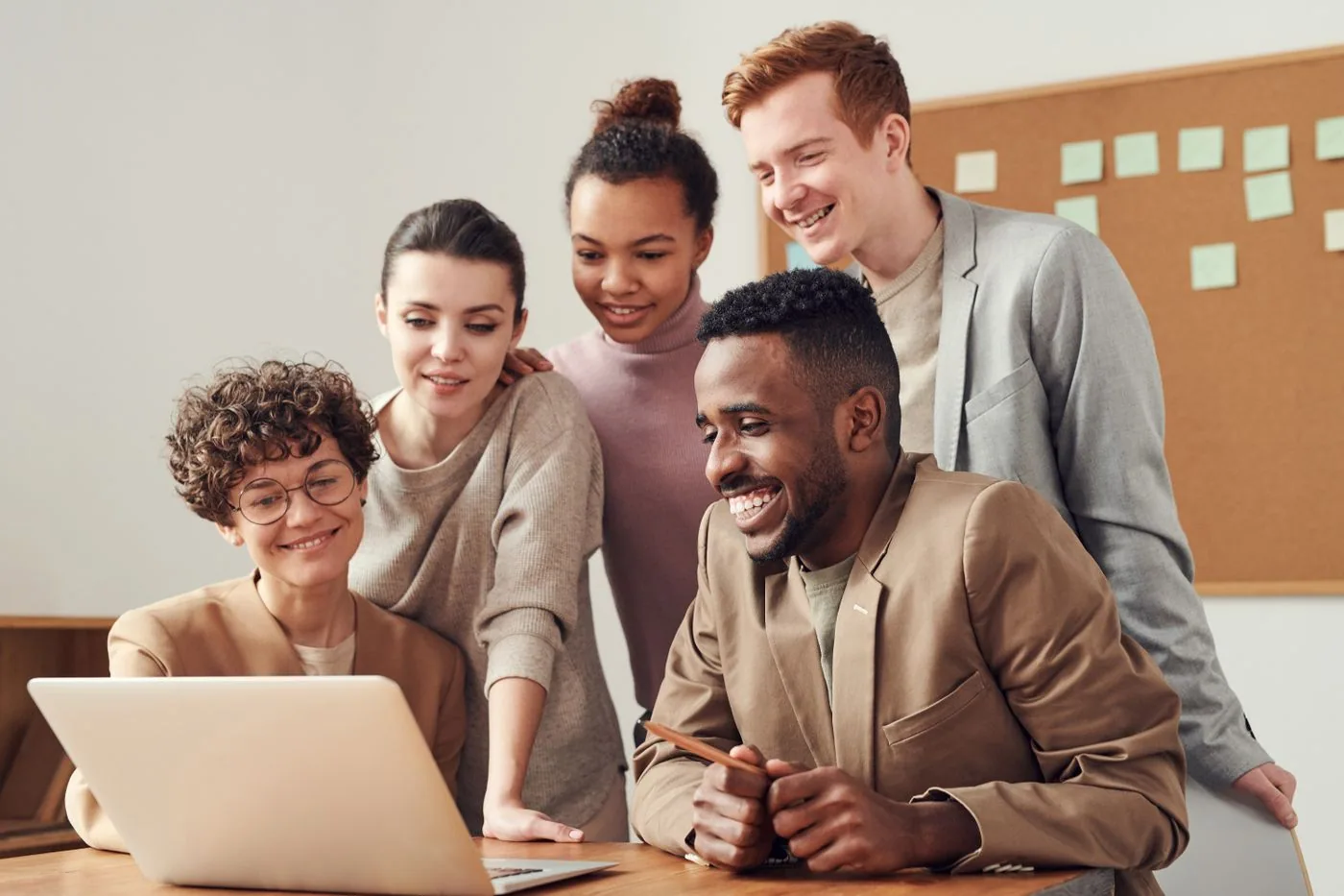 Imagen ilustrativa. Equipo de trabajo sonriente reunido frente a un computador portátil.